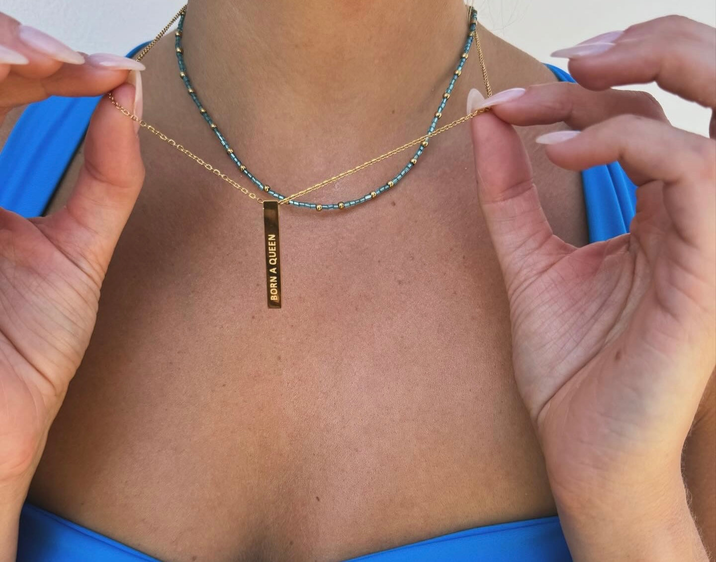 Gold born a queen pendant stacked with blue bead necklace 